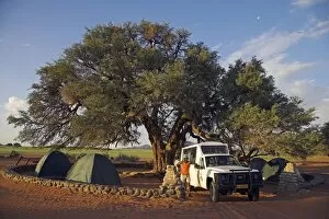A safari guide stands in front of his Land Cruiser