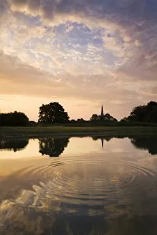 Salisbury Cathedral Spire and a beautiful dawn sky reflected in a rippled pond, Salisbury