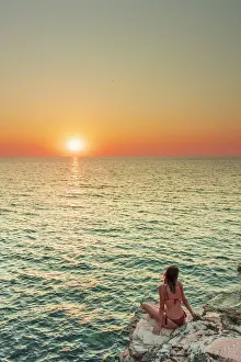 Geography Prints: San Vito lo Capo, Sicily. A person enjoying the view of the sun setting along the rock