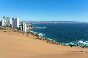 Sand dunes with high-rise buildings on coast and distant view of Vina del Mar and Valparaiso, Concon