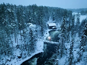 Elevated Collection: Santa Claus with lantern on the suspended bridge above the frozen rapids, Myllykoski, Juuma