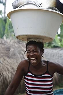 African Woman Gallery: A Sao Tomense woman laughs while carrying her washing up on her head