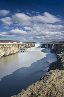 Scenic view of Selfoss waterfall amidst rocky cliffs against cloudy sky, Northeast