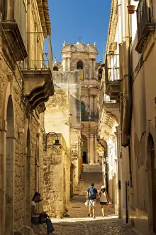 Baroque Style Prints: Scicli, Sicily. People walking in the narrow streets with San Giovanni Evangelista