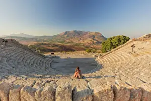Mediterranean Area Prints: Segesta, Sicily. A woman sitting alone in the greek theater of Segesta at sunset