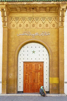 Morocco Collection: Senior woman with hijab sitting outside a doorway at majestic gold colored entrance of medina