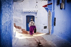 Morocco Collection: Senior woman with hijab walking among blue buildings of medina, Chefchaouen, Morocco
