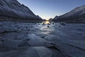 Gryllefjord Prints: Sheets of ice of the frozen sea frame the snowy peaks at sunset Gryllefjord Senja Tromso Norway Europe