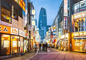 The City at Night Gallery: Shinjuku, Tokyo, Kanto region, Japan. Illuminated neon signs at dusk and Cocoon Tower
