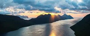 Mountain Peak Prints: Silhouette of Kunoy island lit by sunset reflected in the sea from Klakkur mountain