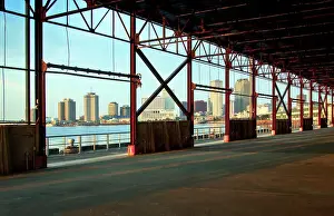 Mississippi River Prints: The skyline of New Orleans is visible thru the steel frame of an old factory building located in the newly developed