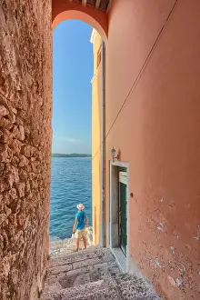 Dalmatian Prints: small arched opening overlooking the sea along the streets of Rovinj, tourist admires