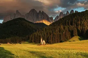 The small chapel of San Giovanni in Ranui taking the last light of the day with the imposing Odle mountains in the background. Dolomites, Italy