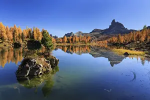 Small rock island emerging from Lago Federa lake with Becco di Mezzoda in the background
