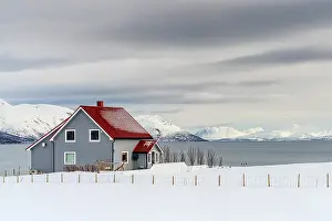 Cloudscape Prints: Snow capped mountains and a lone traditional cabin overlooking the arctic sea
