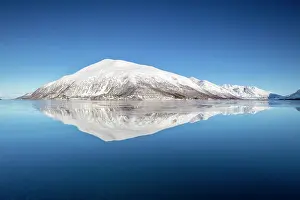 Troms Prints: Snow-covered mountains with a perfect reflection in flat calm waters