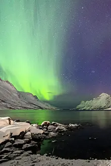 Geomagnetic Storm Prints: Snowy beach and mountains along Ersfjorden under a bright starry sky with Northern Lights