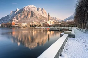 Snowy lakefront of Lecco and San Martino Mountain reflected in Como lake, Lecco province Snowy lakefront of Lecco and San Martino Mountain reflected in Como lake, Lecco province