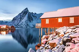 Lifestyles Prints: Snowy mountains and traditional rorbu reflected in the cold sea at dusk