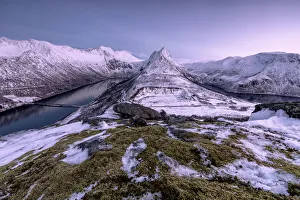 The snowy peaks above the frozen sea framed by the soft lights of dusk Gryllefjorden The snowy peaks above the frozen sea framed by the soft lights of dusk Gryllefjorden