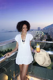 Images Dated 11th October 2012: South America, Brazil, Rio de Janeiro, a model with a cocktail stands over Copacabana