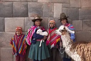 South America, Peru, Cusco. Quechua people standing in front of an Inca wall, holding