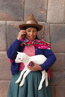 Outfit Prints: South America, Peru, Cusco. A Quechua woman standing in front of an Inca wall, holding