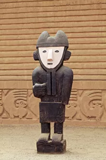 South America, Peru, La Libertad, Trujillo, a wooden statue in front of a carved adobe