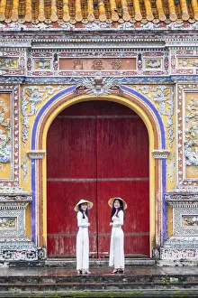 Model Prints: Southeast Asia, Vietnam, Hue. Two young women wearing Ao Dai dresses stand next to an