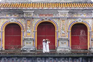Southeast Asia, Vietnam, Hue. Two young women wearing Ao Dai dresses stand next to an