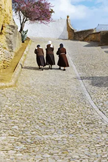 Spain, Andalucia, Malaga Province, Ronda, Three nuns walking up cobbled street