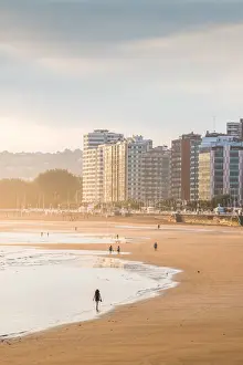 Biscay Prints: Spain, Asturias, Gijon. Tourists walking in Playa de San Lorenzo at sunrise