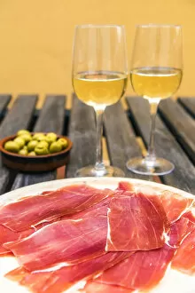 Spanish ham or jamon iberico served with glasses of white wine and olives in a tapas bar