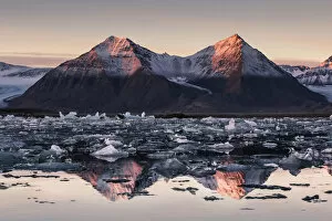 Spitsbergen, Svalbard, Norway. Mountains reflecting in the fjord at sunrise, with