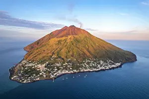 Crater Prints: Stromboli village with black smoke rising from the crater of the volcano