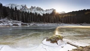 a suggestive sunset at Karersee where the last sun reflected on the iced lake, Bolzano province
