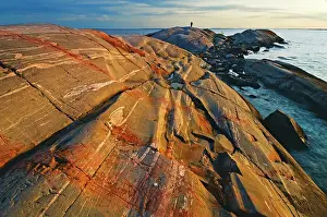 East Prints: sun setting on rocky island in Georgian Bay with man in the distance South of Philip Edward Island Ontario