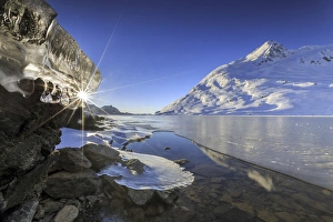 The sun shining through icicles on the shores of Lake Bianco, Canton of Graubunden The sun shining through icicles on the shores of Lake Bianco, Canton of Graubunden