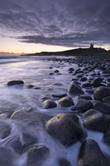 Northumberland Prints: Sunrise at Embleton Bay boulder beach with Dunstanburgh Castle beyond, Northumberland