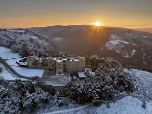 Sunrise over snow covered Castle Drogo on a chill winter morning, Dartmoor National Park, Devon, England. Winter (December) 2023