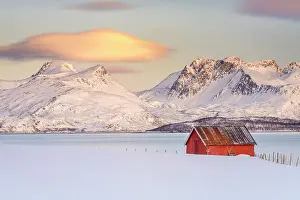 Mountain Peak Prints: Sunrise over snowcapped mountains and a red fisherman cabin along the fjord