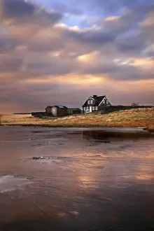 Sunset in Arnastapi, Iceland. Typical Icelandic Farm reflected in the frozen lake