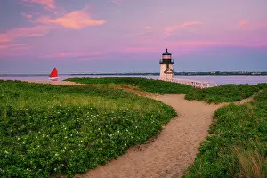 Brant Point Light Prints: Sunset over Brant Point Lighthouse with red sailboat on Nantucket Island
