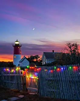 Eastham Prints: sunset over Nausert Beach Lighthouse with holiday lights on beach fence