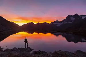 Trekker Prints: Sunsetscape of an hiker at Confinale pass lake during a summer sunset