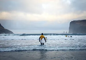 Tjornuvik Prints: A surfer on the sandy beach of Tjornuvik walking towards the ocean