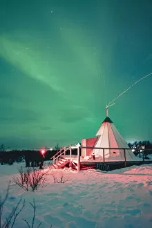 Images Dated 25th May 2022: Swedish Lapland, Abisko National Park. Northern Lights over a typical teepee in the snow, winter