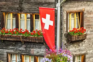 Images Dated 13th September 2021: Swiss flag with typical wooden house decorated with flowers behind, Zermatt, Valais