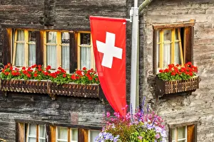 Ski Resort Prints: Swiss flag with typical wooden house decorated with flowers behind, Zermatt, Valais