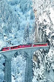 Railway Track Prints: Swiss red train running on Landwasser viaduct from a tunnel carved on steep mountain